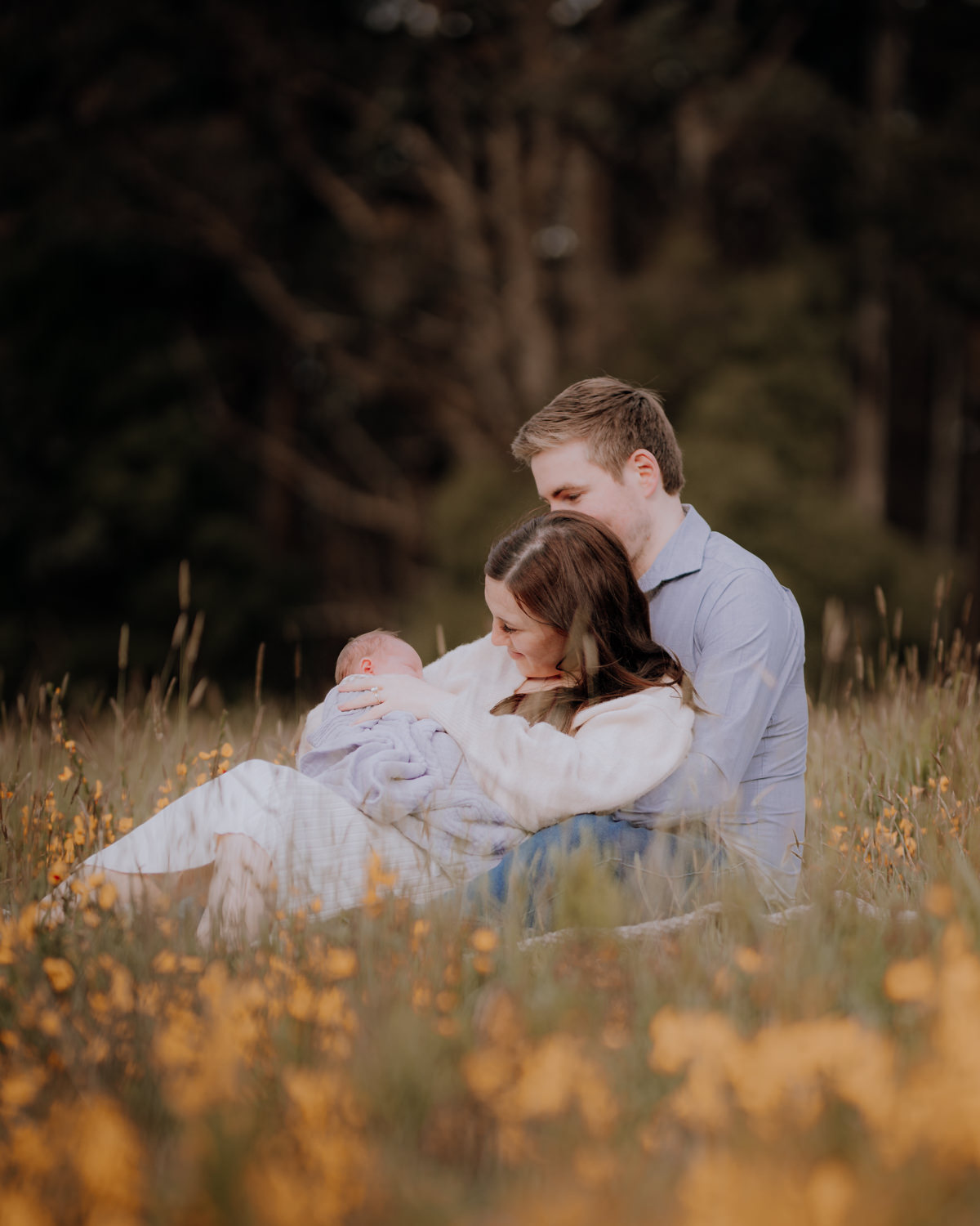 Couple snuggling their newborn in a field at their newborn photography session in the Dandenong Ranges